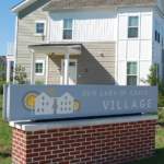 Exterior shot of residential building with Out Lady of Grace Village sign