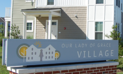 Exterior shot of residential building with Out Lady of Grace Village sign