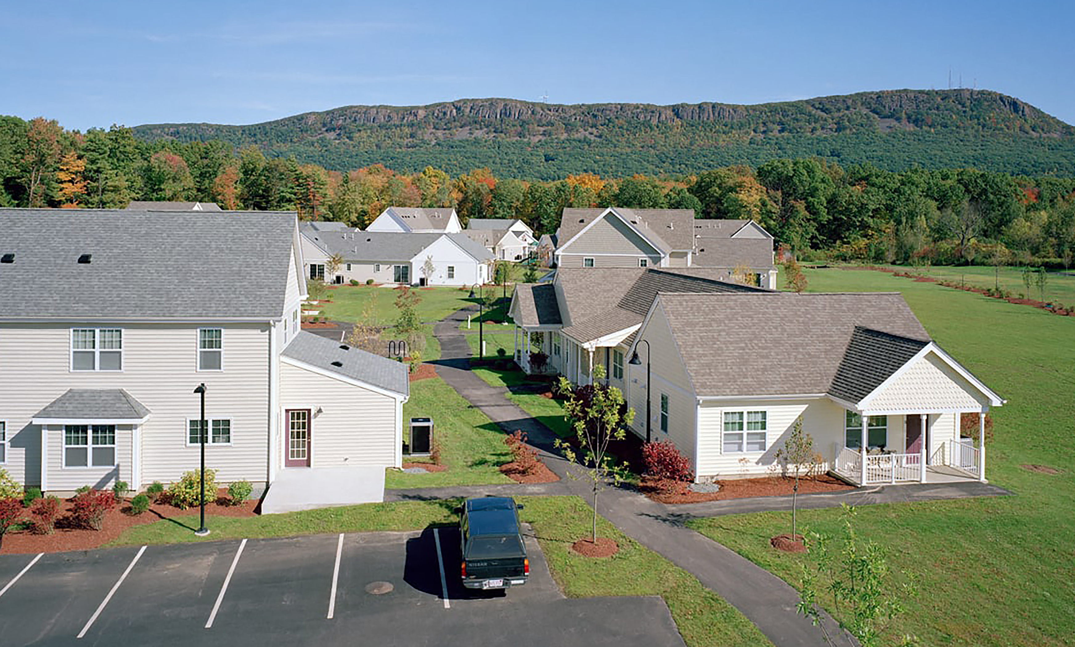 overhead exterior shot of Treehouse at Easthampton Meadown housing development, 5 home structures with white siding and grey roofs in photo