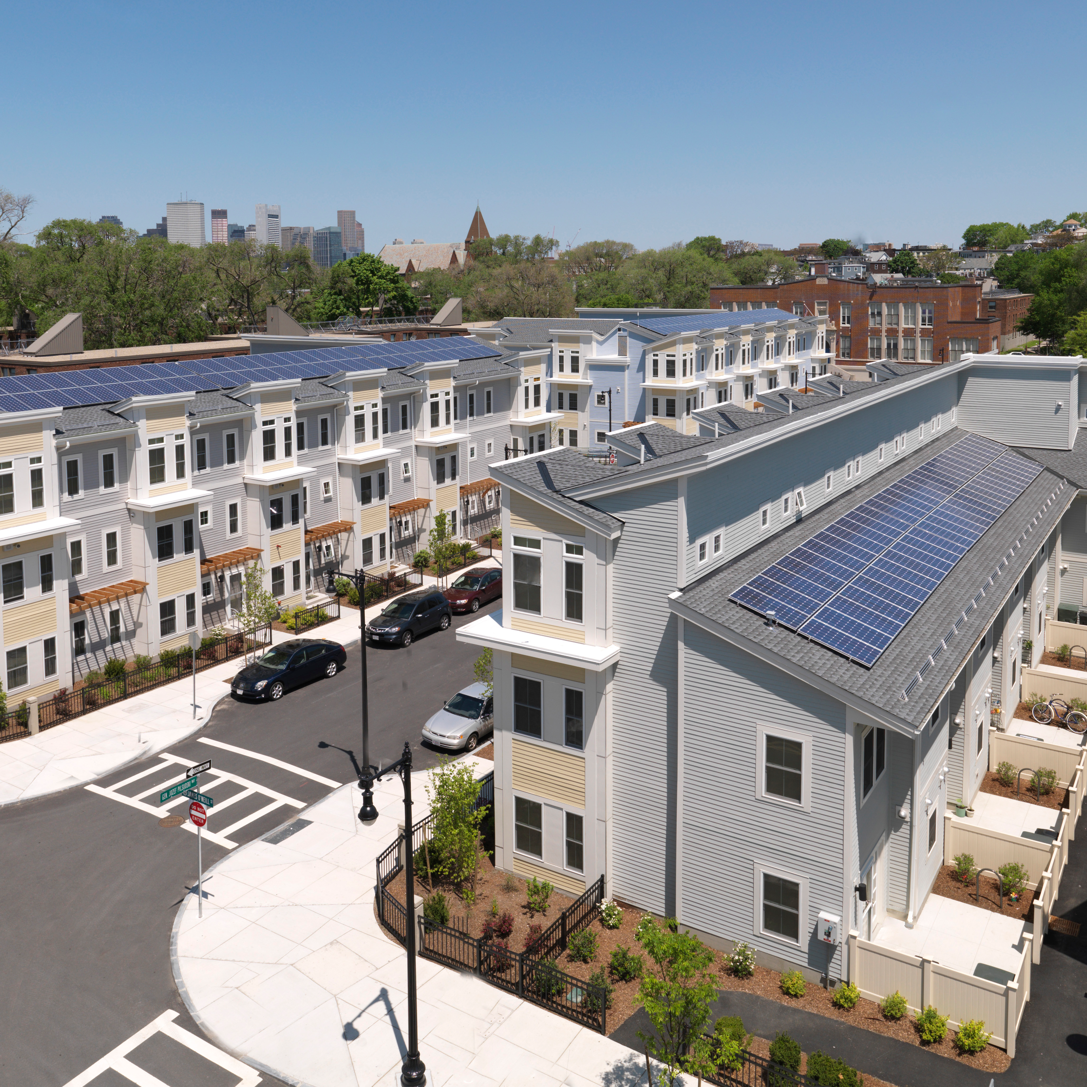 top down view of a neighborhood with condos on both sides of the street and solar panels on rooftop