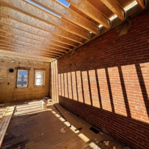 interior shot of a gutted rowhome with exposed brick and no roof