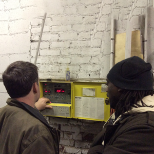 2 men looking at control panel in boiler room