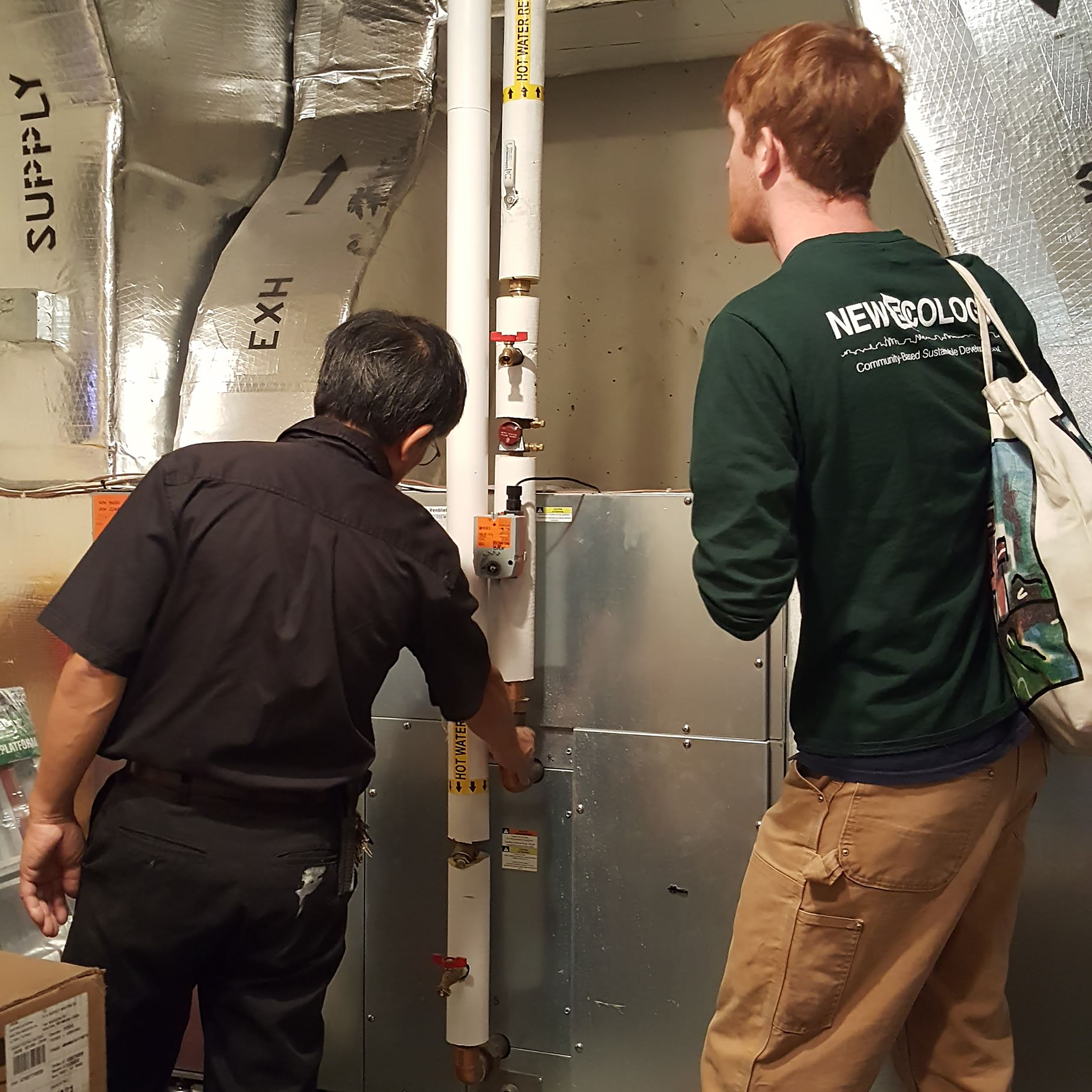 2 men in a boiler room with hot water piping