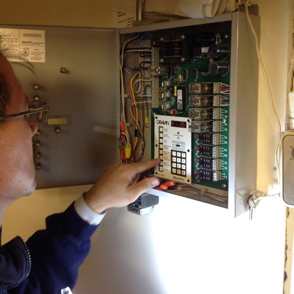 man adjusting controls in boiler room