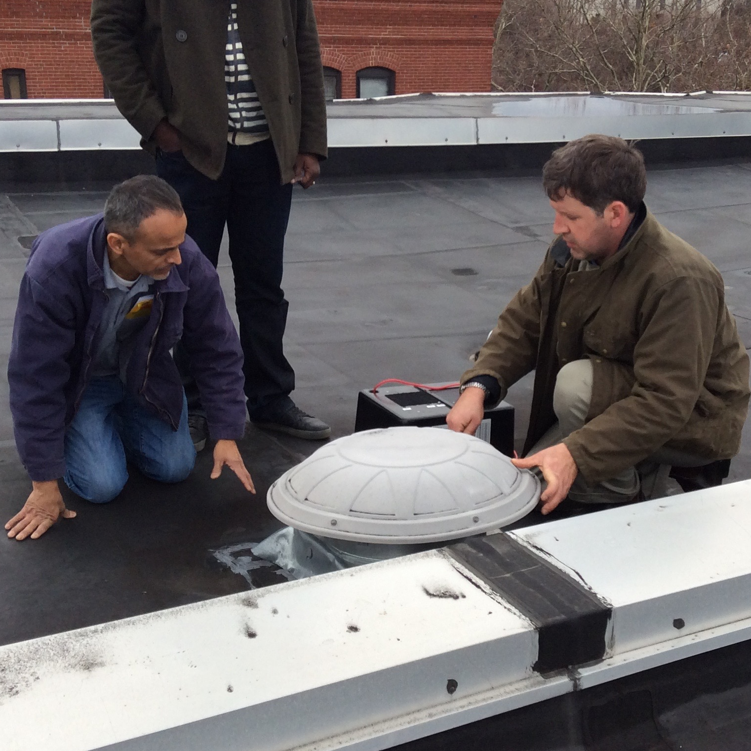photo of 2 men on rooftop inspecting a roof vent