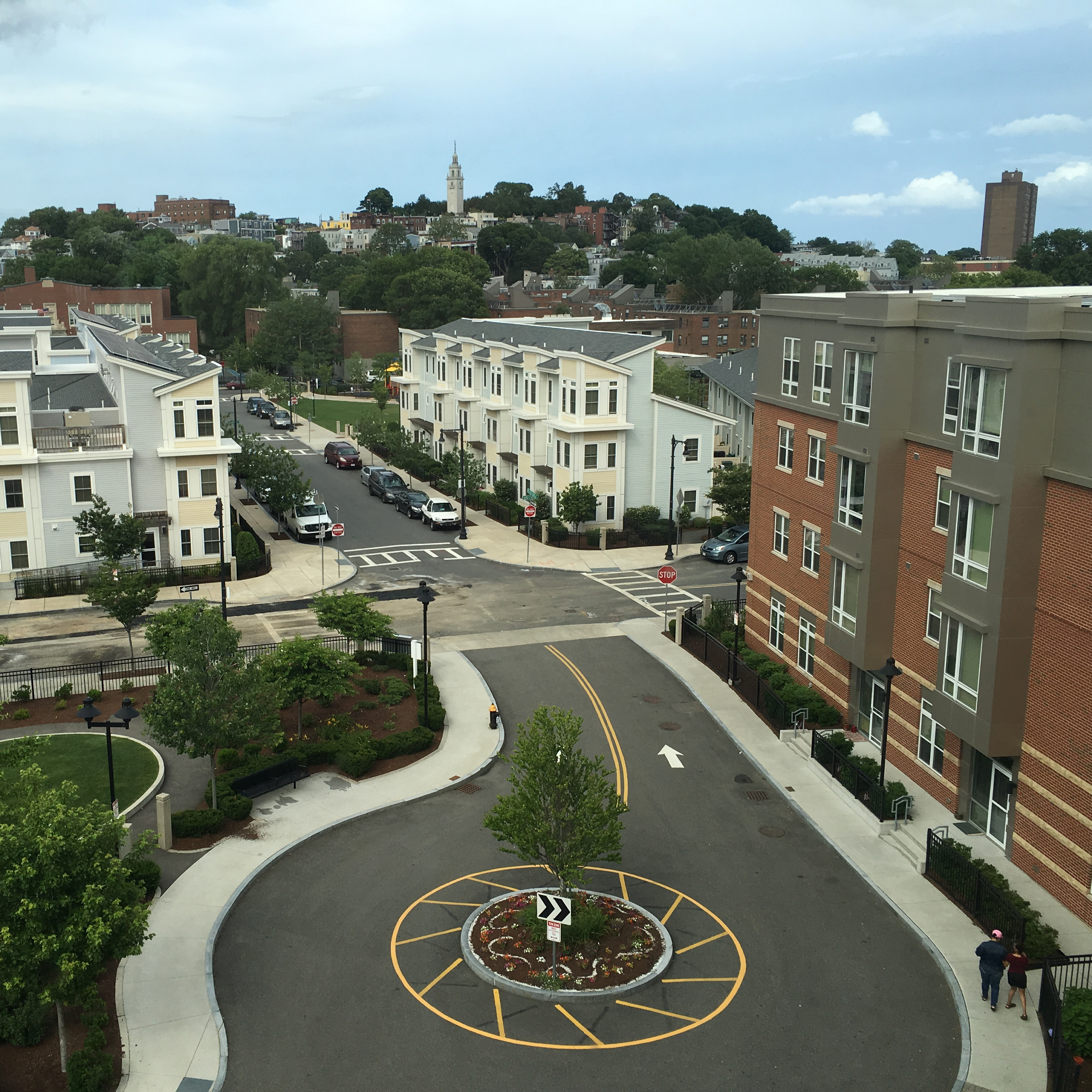 overhead shot of a neighborhood including a multifamily housing building next to a small rotary, condos in the background